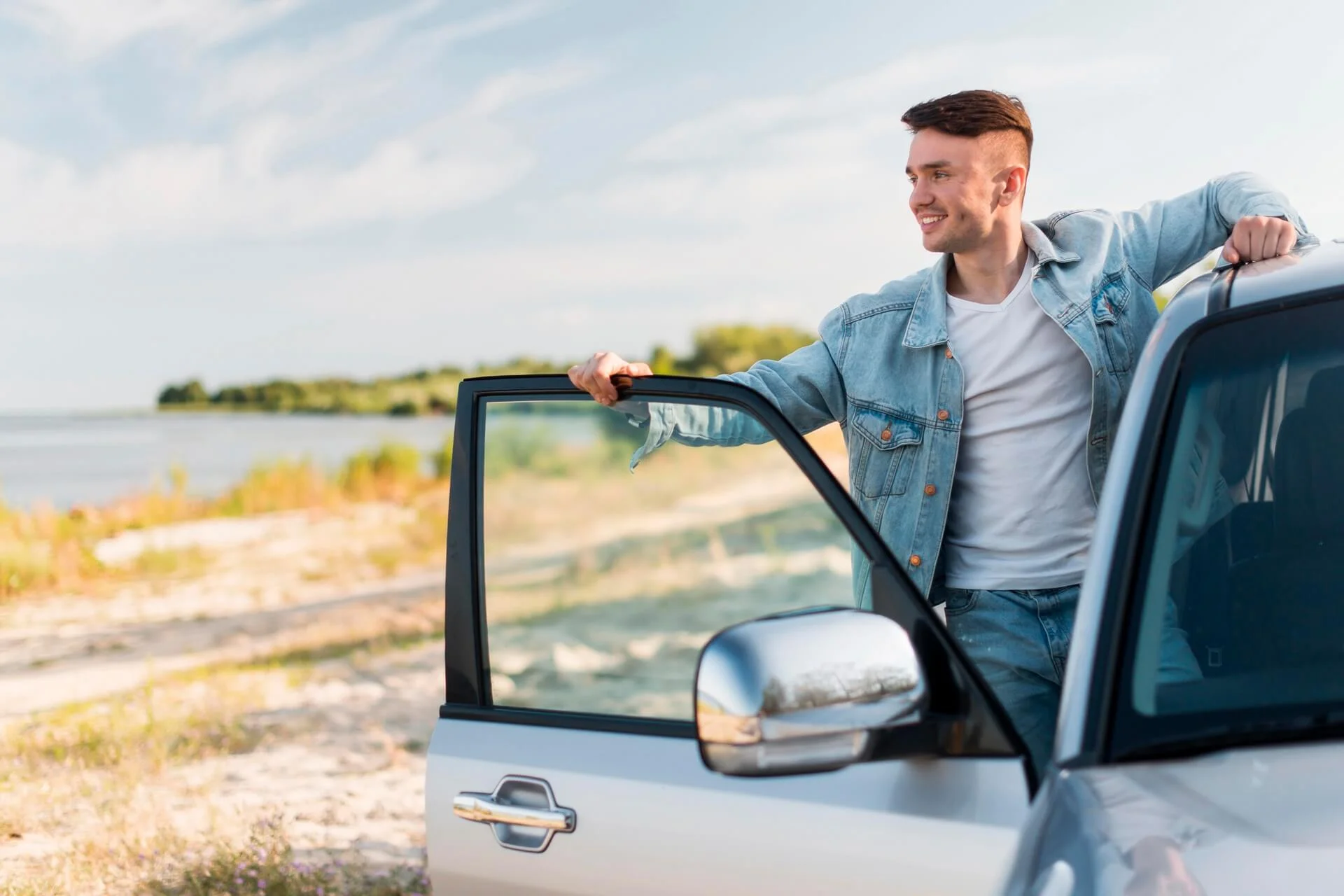 Homem sorrindo posando com carro