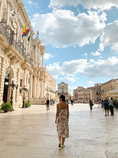 Mulher andando em praça cheia de turistas em Catania, Sicília, Itália